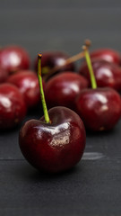 Red cherry fruit on a black wooden table.