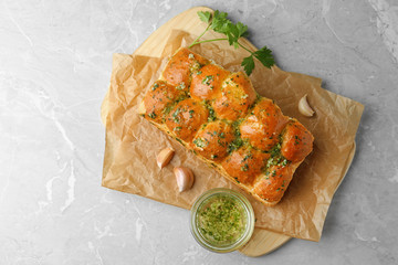 Buns of bread with garlic and herbs on grey table, flat lay