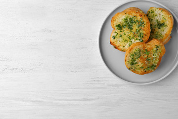 Slices of toasted bread with garlic and herbs on white wooden table, top view. Space for text