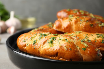 Plate of bread loaves with garlic and herbs on grey table, closeup
