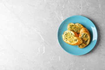 Slices of toasted bread with garlic, cheese and herbs on grey table, top view. Space for text