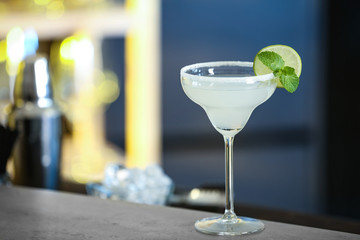 Fresh alcoholic cocktail with lime and mint on bar counter, space for text