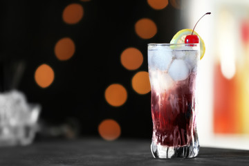 Fresh alcoholic cocktail with lemon and cherry on bar counter, space for text