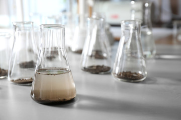 Glassware with soil samples and extract on grey table. Laboratory research