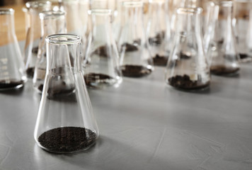 Glassware with soil samples on grey table. Laboratory research