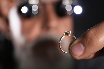 Male jeweler examining diamond ring in workshop, closeup view