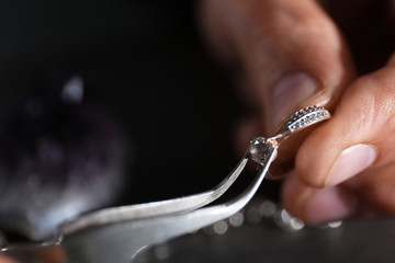 Male jeweler examining diamond ring in workshop, closeup view