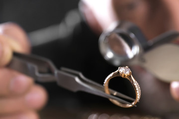 Male jeweler examining diamond ring in workshop, closeup view