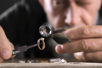 Male jeweler evaluating diamond ring in workshop, closeup view