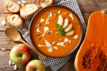 Homemade spicy hot pumpkin and apple soup with seeds close-up in a bowl. Horizontal top view