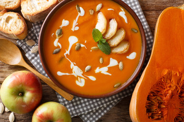 Traditional autumn pumpkin and apple soup with seeds close-up in a bowl. Horizontal top view