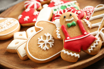 Tasty homemade Christmas cookies on wooden plate, closeup view