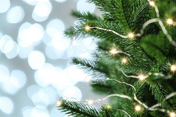 Fototapeta na wymiar Decorated Christmas tree against blurred lights on background. Bokeh effect