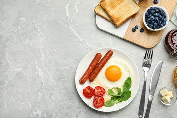 Tasty breakfast with fried egg on light grey marble table, flat lay. Space for text