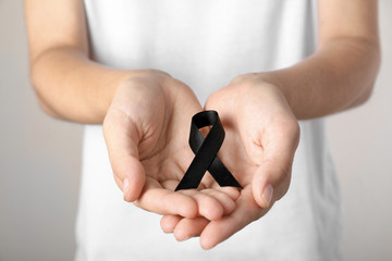 Young woman holding black ribbon, closeup. Funeral symbol