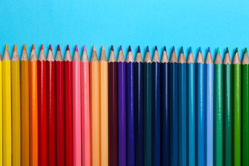 Colorful pencils on light blue background, flat lay