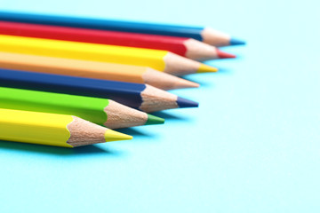 Colorful pencils on light blue background, closeup