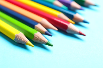 Colorful pencils on light blue background, closeup