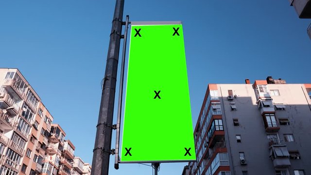 Blank, empty advertisement flag, banner on street with buildings. Promotion and advertisement mock up, vertical poster with green screen, alpha channel. 