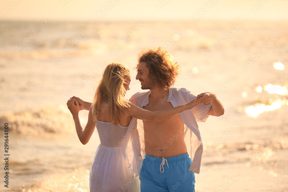 Poster Young couple dancing on beach at sunset