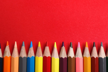 Flat lay composition with color pencils on red background. Space for text