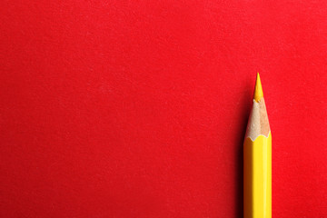 Yellow pencil on red background. Space for text