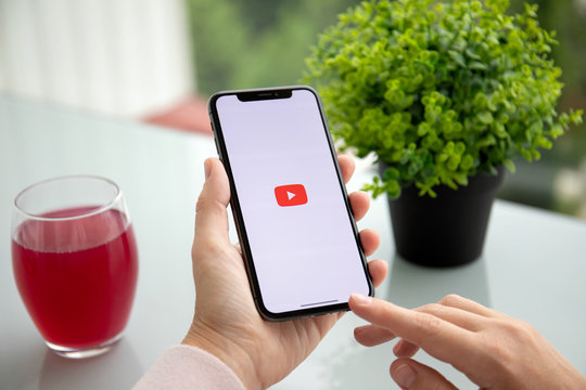 Woman holding iPhone X with streaming media video service YouTube