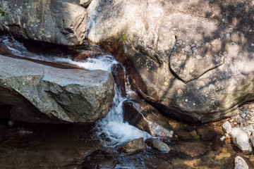 stream running down giant rocks on the rocky creek on a sunny day