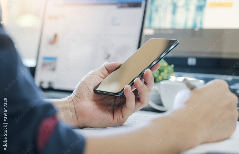 Poster man using smartphone while working at modern office, blank screen for graphics display.