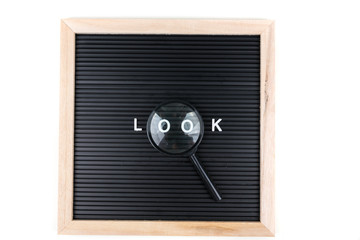 Black white letters sign board with the word look spelled out in magnifying glass