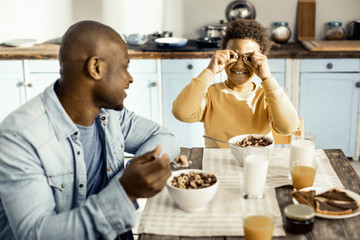 Smiling dad watching frisky boy playing with cereal.