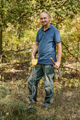 Man with electronic metal detector device, outdoor background.
