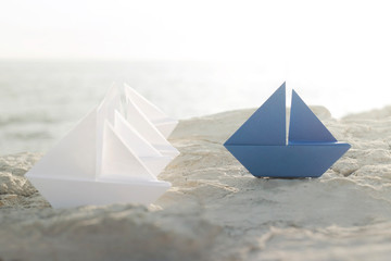 blue origami boat stands on white boats, concept of difference, success, leadership