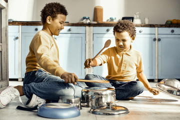 Children sitting on the kitchen floor and playing with creative resources.