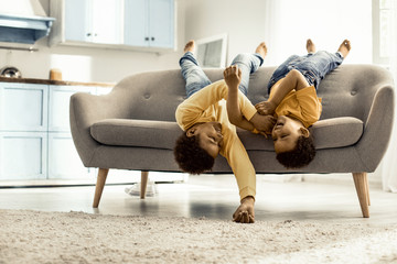 Boys lying across the couch upside down barefoot and laughing.