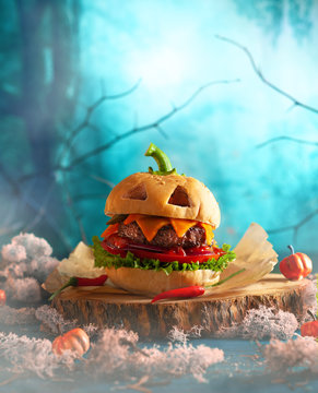 Naklejki Halloween party burger in shape of scary pumpkin   on natural wooden board. Halloween food concept.
