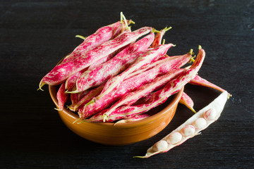 Pink spotty bean pods (Phaseolus) on a wooden black table. Harvest season