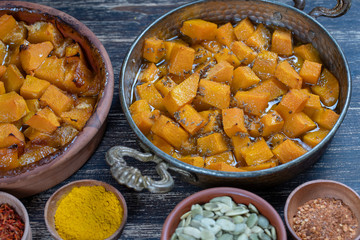 Baked yellow pumpkin with honey, anise, olive oil and spices on a plate on the wooden table. Vegetarian food. Closeup