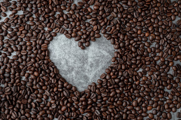 coffee beans with heart shape sign on dark wall texture background.