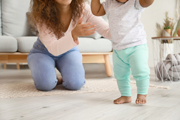 Cute little baby learning to walk at home