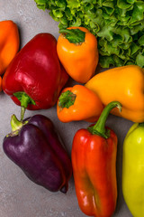 Bell Peppers, sprig green lettuce on grey background