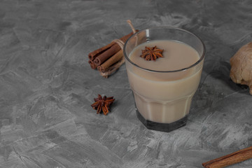 Traditional indian masala chai tea with ingredients. Cinnamon, cardamom, anise, ginger. On a gray background, horizontal orientation.