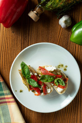 bruschetta with bell pepper, basil, pesto sauce and mozzarella on a white plate on a wooden background. Italian restaurant. Top view food photo