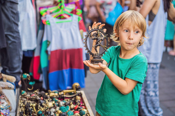 Boy at a market in Ubud, Bali. Typical souvenir shop selling souvenirs and handicrafts of Bali at the famous Ubud Market, Indonesia. Balinese market. Souvenirs of wood and crafts of local residents