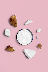 white cream in a jar on with coconut on trendy pink background. beauty and health care concept. Minimalistic flat lay with copy space. Top view. Cosmetic natural skin care