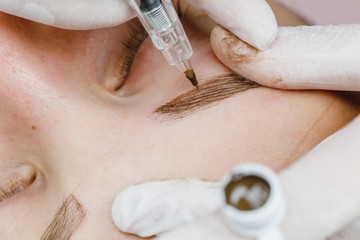 Permanent makeup, tattooing of eyebrows. Cosmetologist applying make up