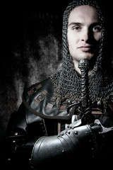 Portrait of handsome knight in suit of armour looking at camera with candles in background