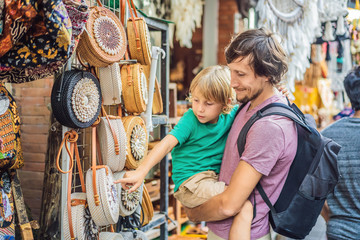Dad and son at a market in Ubud, Bali. Typical souvenir shop selling souvenirs and handicrafts of Bali at the famous Ubud Market, Indonesia. Balinese market. Souvenirs of wood and crafts of local