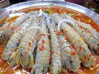 Top view of fresh mantis shrimp topped with spicy seafood dipping sauce for sale in the restaurant at Thailand, abstract background, Close up raw sea crayfish  for sale at seafood market ready to eat 