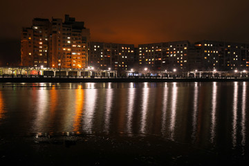 Fototapeta na wymiar City embankment at night. Lights in the windows of apartments and lanterns. Winter is coming.